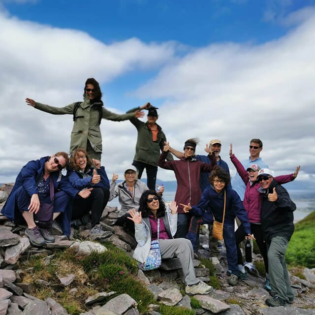 Vagabond group posing with their arms in the air at a viewing point in Rossbeigh