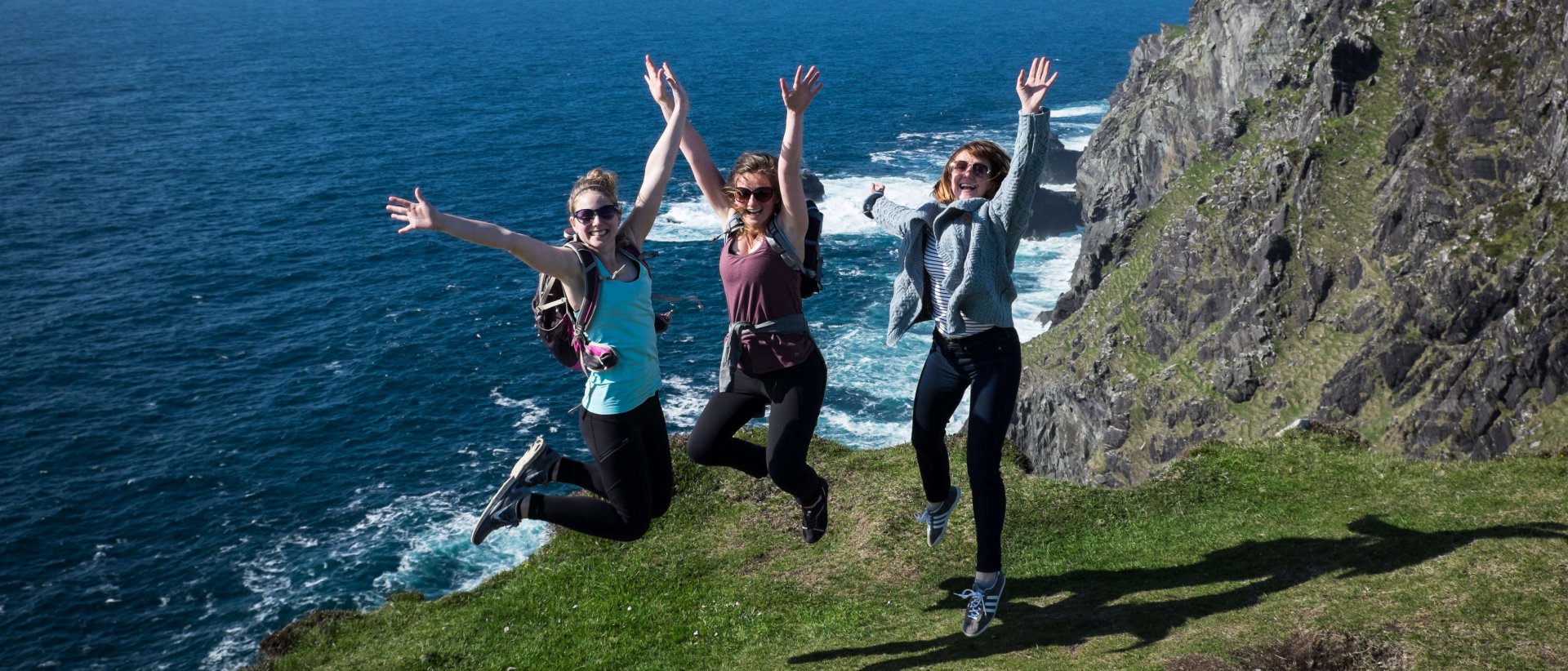 Three Vagabond guests jumping for joy on Bray Head, Wild Atlantic Way, Kerry in Ireland