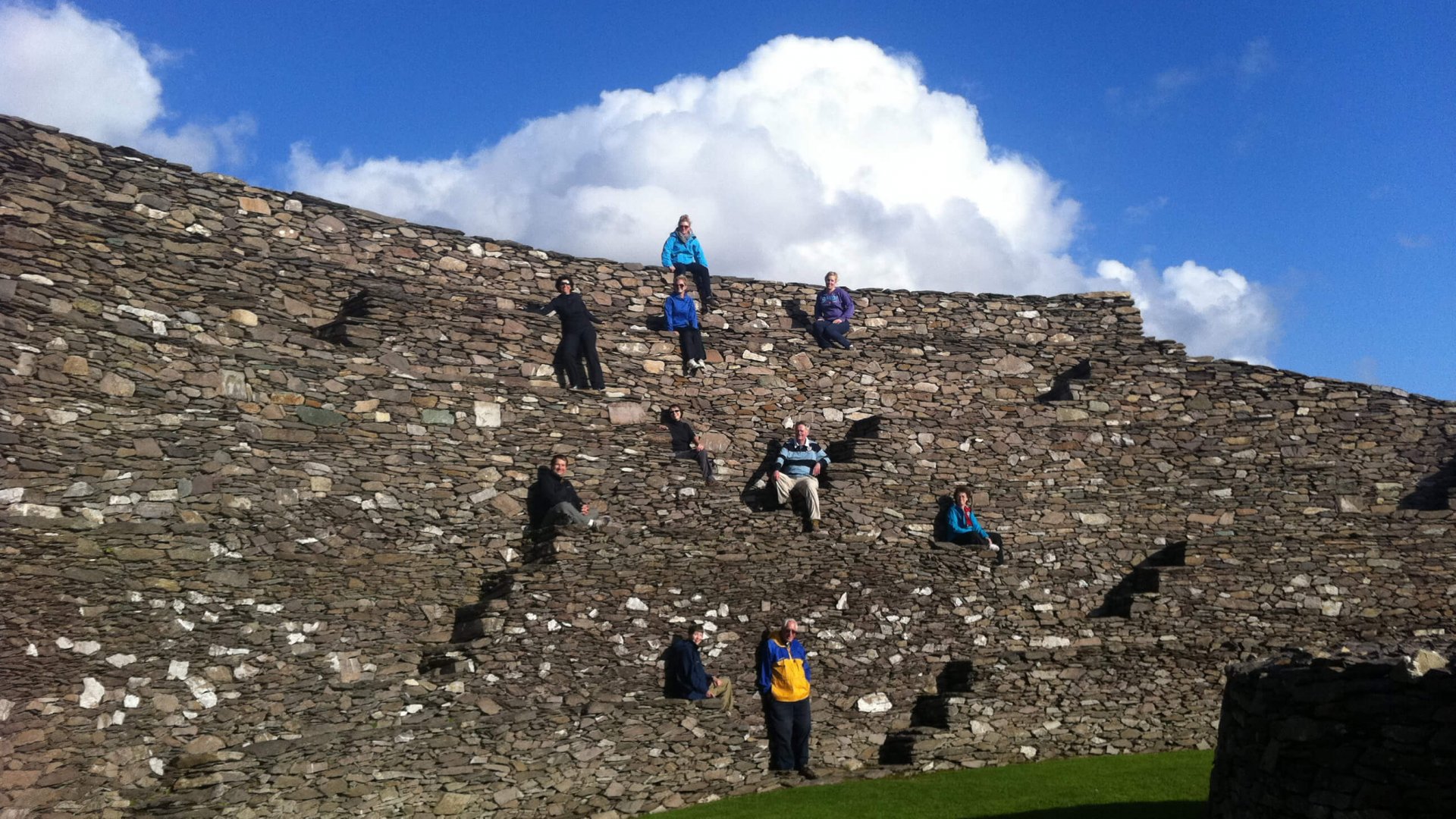 Vagabond Tours group standing at different levels of a stone wall on the interior of Grianán of Aileach fort in Donegal